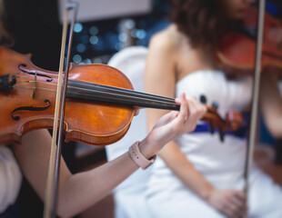 Female violin player, fiddler violinist with a bow performing music on stage during concert with...
