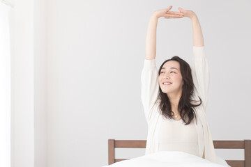 朝、ベッドルームでストレッチして体をほぐし起きる準備 をしている女性