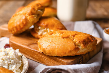 Board of tasty sochniki with cottage cheese on wooden background