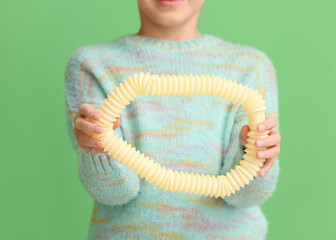 Little girl with yellow Pop Tube on green background, closeup