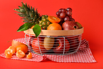 Basket with fresh juicy fruits on color background