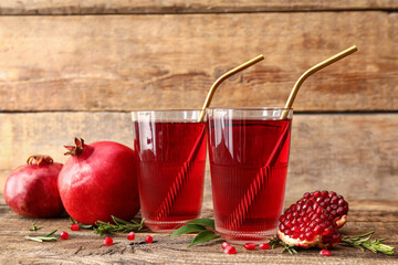 Glasses of delicious pomegranate juice on wooden background