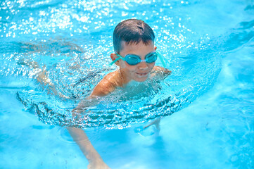 Fototapeta na wymiar Boy in goggles swimming in pool