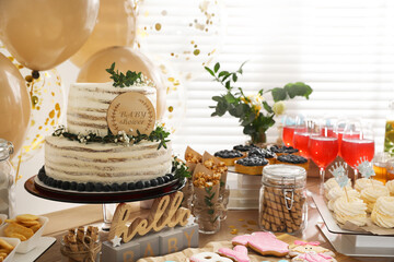 Baby shower party. Different delicious treats on wooden table and decor indoors