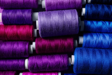 Spools with purple and blue sewing threads, closeup