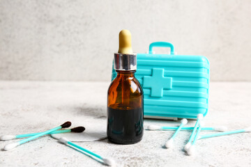 Bottle with iodine, cotton swabs and first aid kid on grunge background