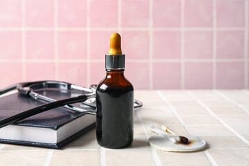 Bottle with iodine, notebook, stethoscope, cotton pad and swabs on tile background