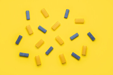 Set of different hair curlers on yellow background
