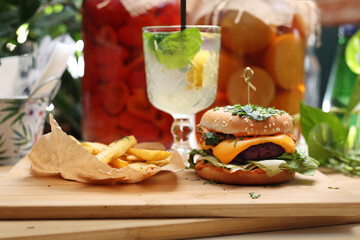 Vegan lunch set. Vege burger, potato fries and lemonade on a wooden cutting board. Plant-based meal, horizontal view.