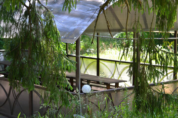 Covered seating area with long wooden table and benches.