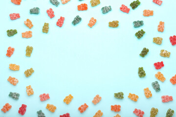 Frame made of different tasty jelly bears on color background