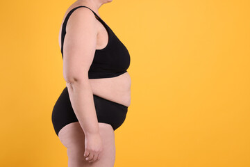 Overweight woman in underwear on orange background, closeup. Space for text