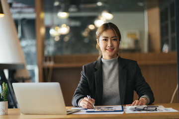 Fototapeta premium Cheerful smiling business woman working with laptop computer while sitting at the desk in modern office.