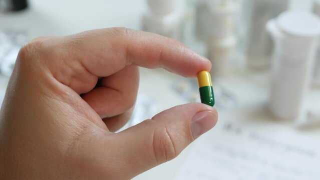 Unrecognizable male's patient hold yellow green pill. Two-piece, hard starch capsules. Health care, pharmacy and treatment concept