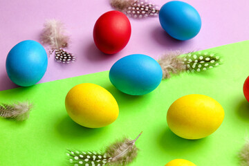 Fototapeta na wymiar Multicolored Easter eggs and feathers on color background