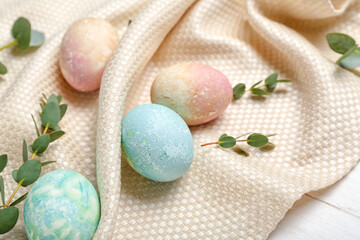 Obraz na płótnie Canvas Painted Easter eggs, eucalyptus branches and napkin on white wooden background