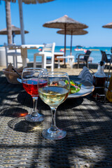 Obraz premium Drinking of cold rose and white wines in lounge bar on sunny sandy beach with blue sea water on background