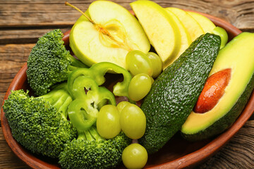 Plate with different vegetables and fruits for St. Patrick's Day celebration on wooden background