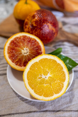 Naklejka na ściany i meble Sicilian sweet juicy yellow and red blood oranges with green leaves close up
