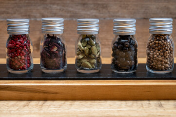Professional set of gin spices in small bottles, pink pepper, hibiscus flowers, juniper berries, cardamom and coriander seeds