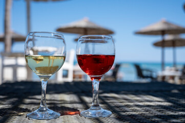 Drinking of cold rose and white wines in lounge bar on sunny sandy beach with blue sea water on background