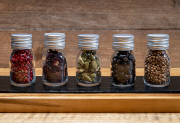 Professional set of gin spices in small bottles, pink pepper, hibiscus flowers, juniper berries, cardamom and coriander seeds