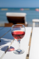 Drinking of cold rose wine in lounge bar on sunny sandy beach with blue sea water on background
