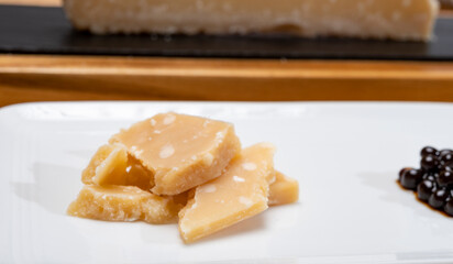 Tasting of 72 months very old Italian parmigiano-reggiano parmesan cheese from Parma  with intense taste with black pearls of balsamic vinegar DOP from Modena.