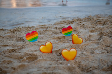 lgbt and yellow hearts in the sand stand on the sea