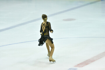 Girl figure skater rolls on a skating rink with artificial ice 
