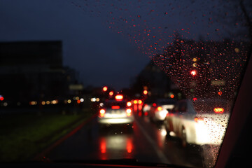 Blurred view of road through wet car window at night. Bokeh effect