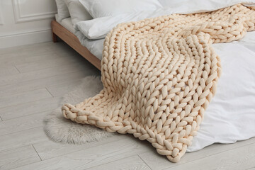Soft chunky knit blanket on bed indoors