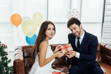 Young couple celebrating new year together, boyfriend gives a present to girlfriend.