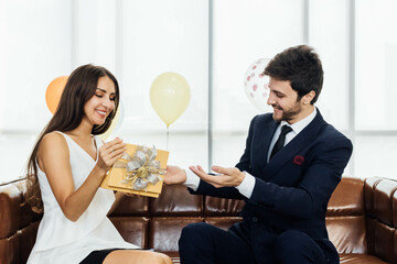 Young couple celebrating new year together, boyfriend gives a present to girlfriend.