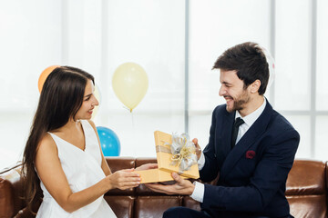 Young couple celebrating new year together, boyfriend gives a present to girlfriend.