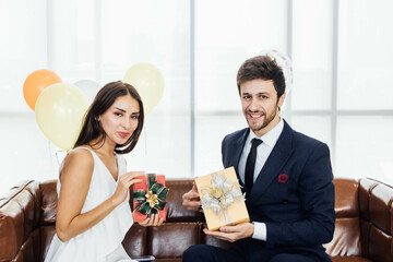 Young couple celebrating new year together, exchanging gifts to each other.