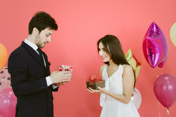 Young couple celebrating new year together, couple exchanges gifts.