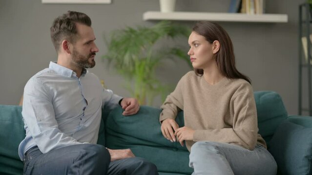 Couple having Serious Conversation while Sitting on Sofa 