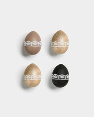 Easter eggs golden, black and beige colored on white background. Symbol Easter holiday, celebration card, dyed chicken egg bright trendy colors and decorated lace tape. Top view, minimal flat lay.