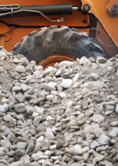 Heavy duty equipment backhoe wheel with large rock pile at construction site