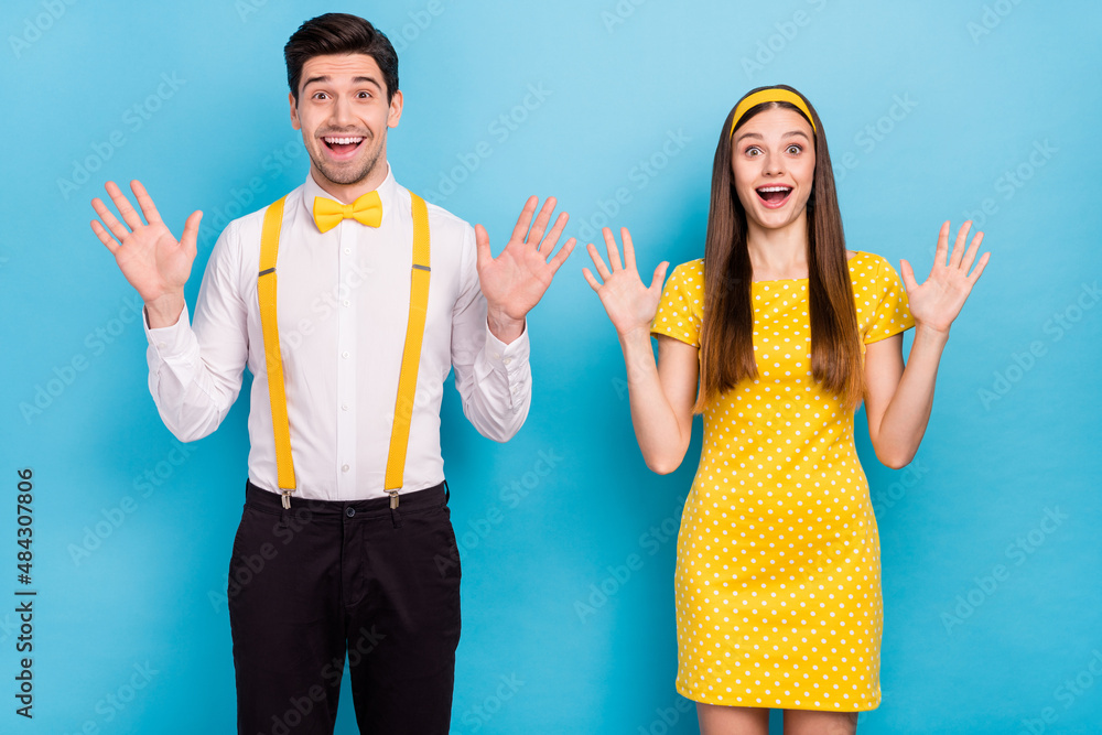 Sticker Portrait of two positive excited partners raise arms palms open mouth isolated on blue color background