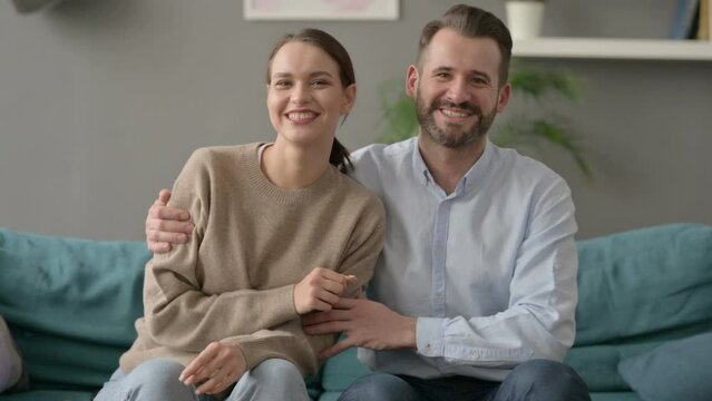 Couple Smiling at Camera While Sitting on Sofa 