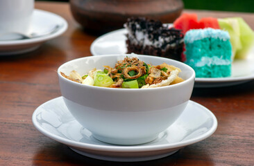 Close up of Bubur Ayam, chicken porridge, on wooden table