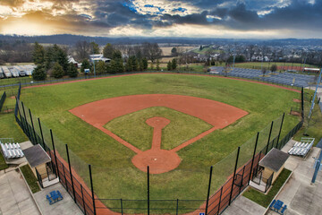 High angle shot of a baseball court surrounded by a net fence at sunset