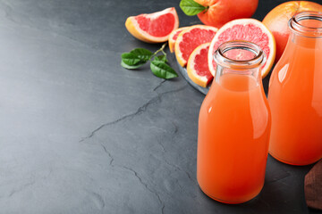 Tasty freshly made grapefruit juice on black table. Space for text
