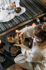 Singing bowls top view, sound healing alternative therapy. Woman playing on percussion metal music...