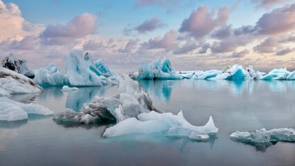 Drifting icebergs in the Jokulsarlon Lagoon in Iceland, with fluffy sunset clouds in the background.