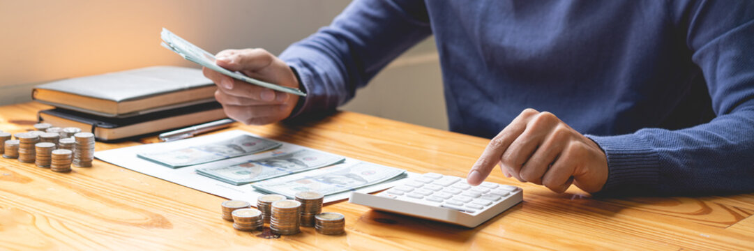 saving concept the guy in the dark blue sweater working on counting cashes and coins that he has been saving up for months