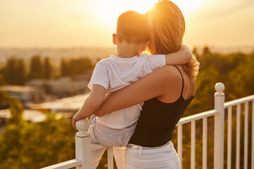 Mother and son admiring sunset in summer