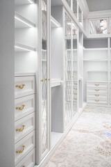 Luxury white walk-in closet with led lamps on shelves and mirror facades with rhombuses and contemporary luster in apartment